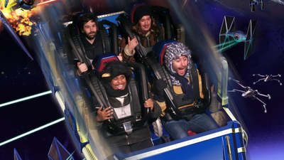 Quatre personnes dans une attraction type grand-huit avec un décor spatial.