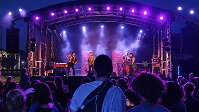 De nuit, des gens dansent dehors devant un concert.