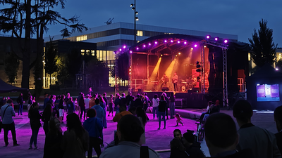 De nuit, des gens dansent dehors devant un concert.