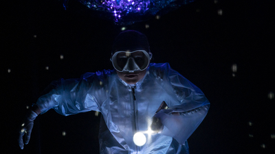 Une femme en tenue de plongée, entourée de lumières bleues.