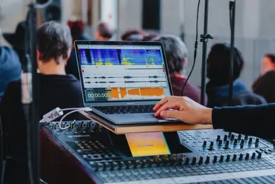 Gros plan sur une ordinateur et une table de mixage sonore.