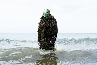 Un homme recouvert d'algues avec un masque marin, dans la mer.