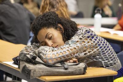 Une jeune femme endormie sur la table dans une salle de classe.