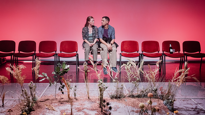 Un couple est assis sur des chaises et des fleurs poussent au premier plan.