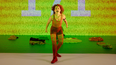 Une danseuse criant devant un écran vert avec le nombre "171" inscrit dessus.