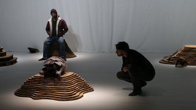 Deux comédiens dans un décor de grotte.