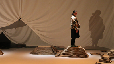 Une comédienne dans un décor de grotte.