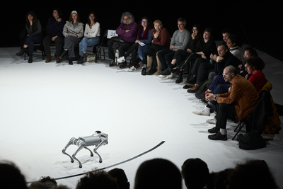 Sur une scène, un chien-robot fixe le public.