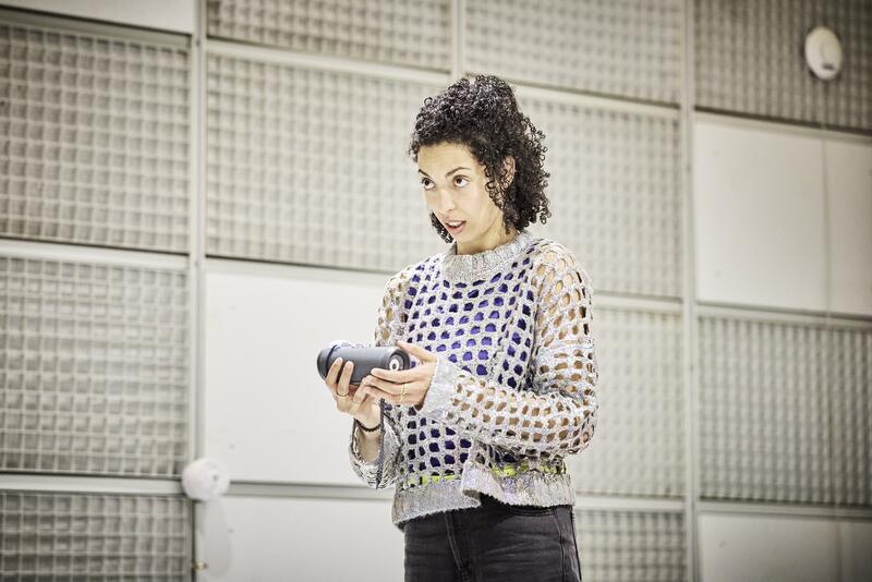 Une jeune femme parle à une enceinte musicale bluetooth