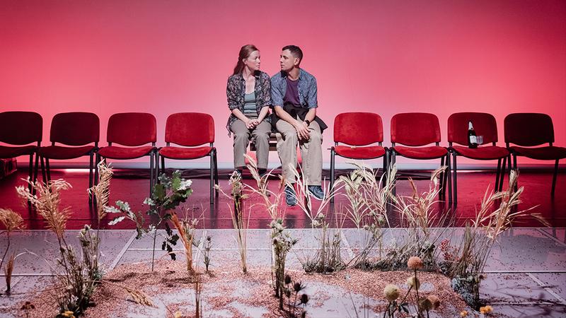 Un couple est assis sur des chaises et des fleurs poussent au premier plan.