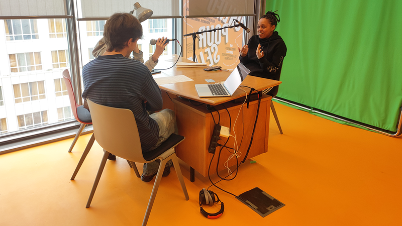 Une femme se fait interviewer derrière un bureau.