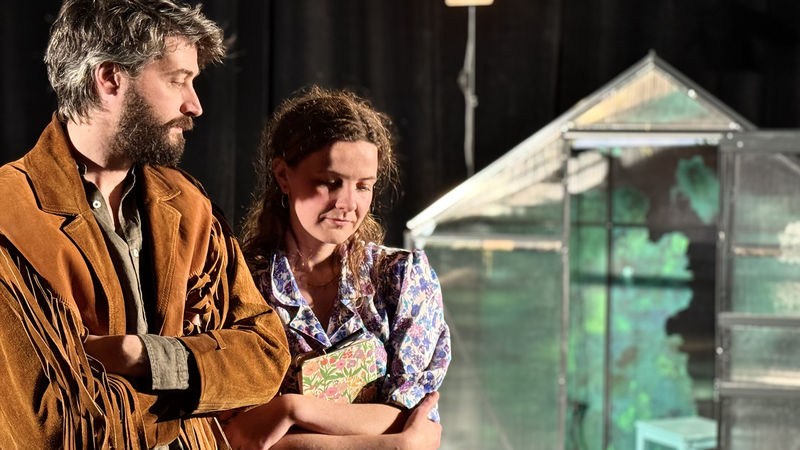 Une femme et un homme se regardent, à l'arrière-plan on distingue une serre.